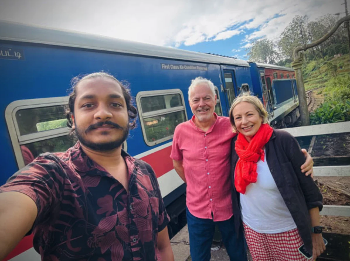 Traveling couple and Sri Lankan driver beside a hill-country train