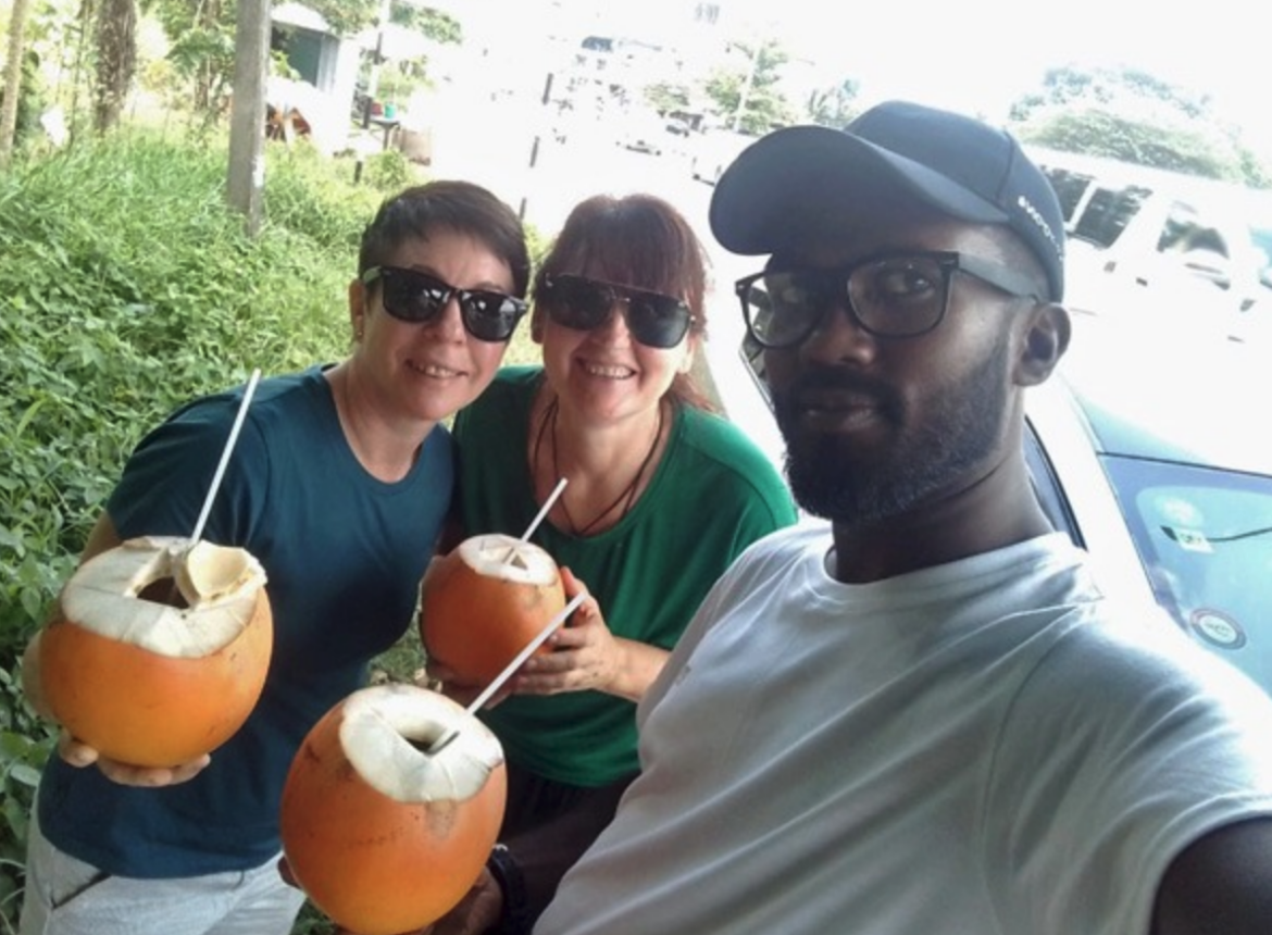 Travelers enjoying fresh king coconuts with their Sri Lankan driver during a private road trip